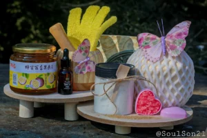 A cozy display featuring white bath salts in a jar, surrounded by decorative butterflies, essential oil, and colorful bath salt crystals