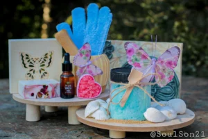 A cozy display featuring blue bath salts in a jar, surrounded by decorative butterflies, essential oil, and colorful bath salt crystals