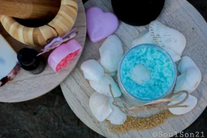 A cozy display featuring blue bath salts in a jar, surrounded by decorative butterflies, essential oil, and colorful bath salt crystals