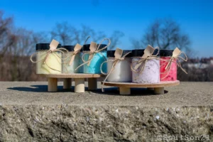 Colorful jars of bath salts, neatly tied with twine, displayed on a wooden stand against a clear blue sky