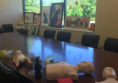 CPR training mannequins and equipment placed on a conference table near a window