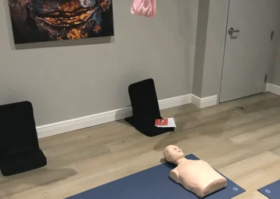 CPR training mannequins placed on a yoga mat in a room with a Buddha painting on the wall
