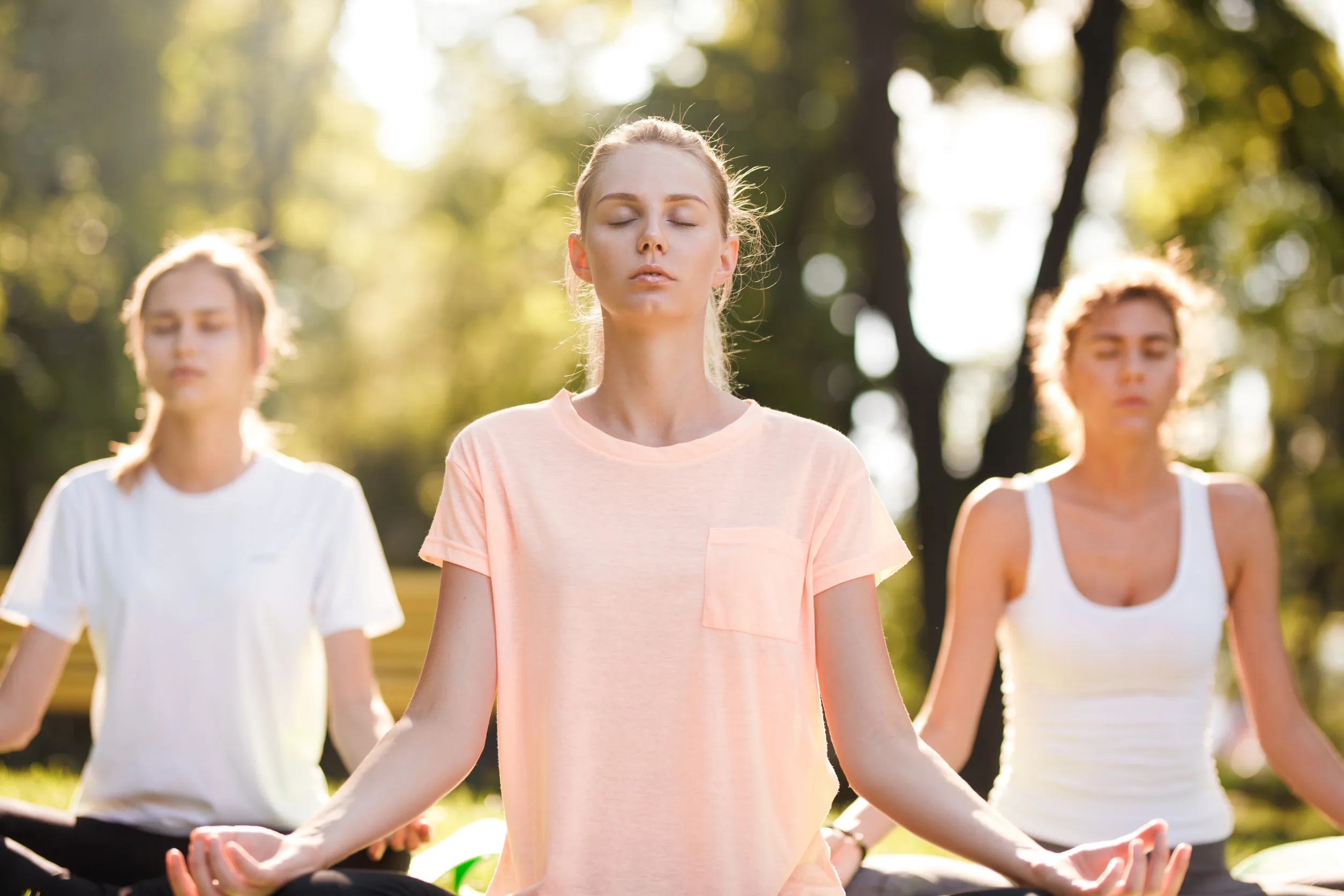 Group of young women practicing yoga, morning meditation in nature at the park