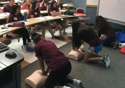 Students practicing CPR on mannequins during a classroom training session